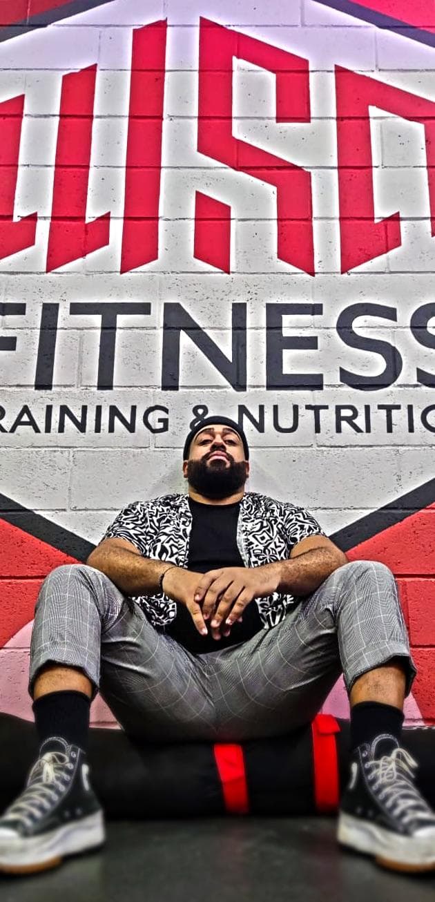 Sidoine, peintre muraliste, assis devant la fresque qu'il a peinte pour WSD Fitness